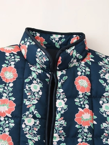 Detail of quilted jacket showing floral print, stand collar and navy blue piping detail