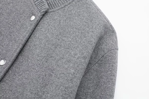Detail of grey bomber jacket with ribbed collar, metallic snaps and wool-blend texture
