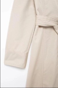Gros plan détaillé sur la texture du sergé beige et la couture de la ceinture de la robe
