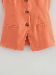 Detail view of coral linen vest featuring three wooden buttons and a stylish V-split hem