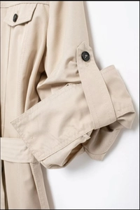 Détail d'une robe chemise kaki avec manches retroussées boutonnées et ceinture à la taille
