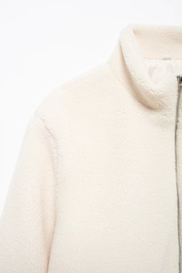 Détail de la veste en polaire blanc cassé avec col montant et fermeture éclair métallique