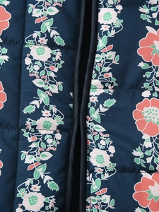 Close-up of floral print quilted fabric with navy base and navy binding detail