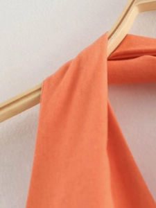 Close-up of orange halter neck top detail showing cotton linen fabric on a wooden hanger