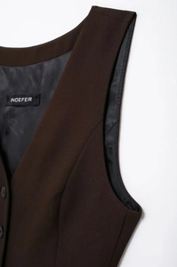 Détail du gilet marron foncé montrant le col en V, la doublure noire et l'étiquette