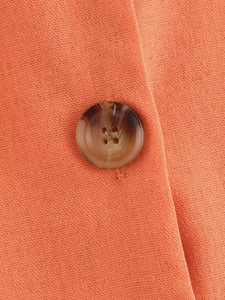 Detail view of orange linen fabric with a brown marble-textured button on the top