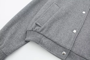 Detail of grey wool-texture bomber jacket with silver metal snaps and ribbed cuffs