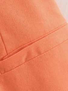 Detailed macro view of bright orange linen fabric texture and fine stitching on the pocket seam