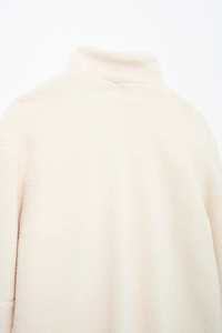 Gros plan du col montant d'une veste en polaire bouclée beige crème de haute qualité