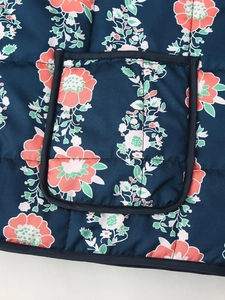 Detail of floral print quilted jacket featuring a patch pocket with black piping