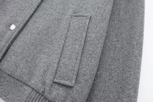 Detail of gray bomber jacket with metallic snap button and textured wool fabric