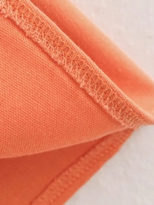 Detailed close-up of double-needle stitching on the orange cotton linen fabric edge