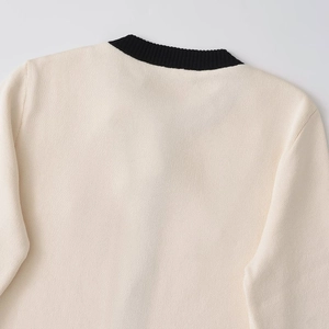 Women's cream knit sweater with black ribbed crew neck and fine stitching detail