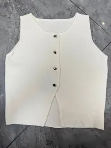 Gros plan sur le gilet en tricot blanc avec boutons argentés et ourlet fendu asymétrique