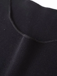 Vue détaillée de la texture maille côtelée et du col rond de la robe noire ajustée