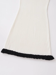 Détail de l'ourlet de robe en tricot crème avec bordure noire à volants et maille côtelée