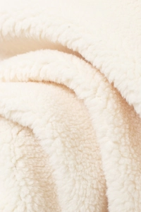 Détail du tissu polaire sherpa blanc crème doux montrant la texture d'une veste chaude