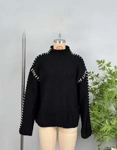 Detail of chunky knit black sweater featuring white contrast stitching and thick texture