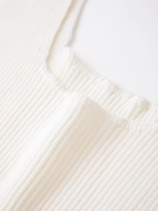 Gros plan détaillé sur la texture en maille côtelée blanche et coutures de la robe