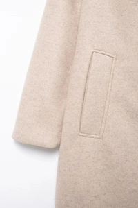 Detail of beige wool blend coat featuring vertical pockets and fine stitching craftsmanship