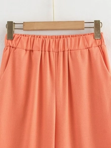 Detail of high-waisted coral cotton linen trousers with elastic waistband and pockets
