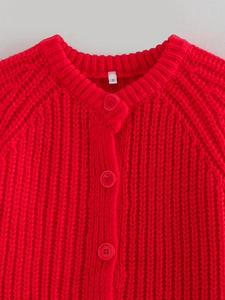 Dettaglio del cardigan in maglia rossa con scollo rotondo e bottoni rossi