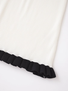 Détail macro du tricot côtelé blanc avec une finition élégante de bordure volantée noire