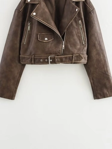 Detail of vintage brown biker jacket featuring a notched lapel and metallic belt buckle