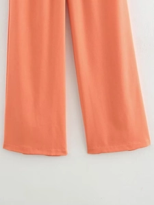 Detailed hem view of coral orange wide-leg trousers featuring neat single-needle stitching