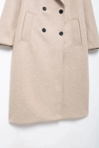 Close-up of oatmeal wool coat fabric showing texture, double-breasted buttons and pockets