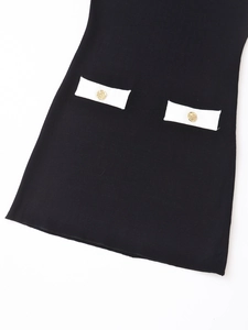 Détail de robe en maille noire avec poches blanches contrastées et boutons dorés gaufrés