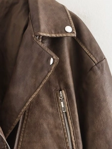 Close-up of vintage brown leather jacket featuring metal snap buttons and zipper details