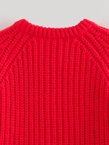 Dettaglio del collo di un maglione rosso a maglia grossa con cuciture fini