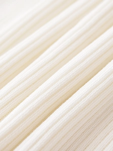 Gros plan sur un tissu en maille côtelée blanche, texture douce et tissage élastique