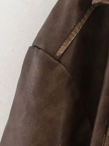 Detail of vintage brown leather jacket showing shoulder stitching and textured fabric