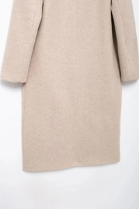 Detailed back view of women's long coat in soft oatmeal wool blend fabric