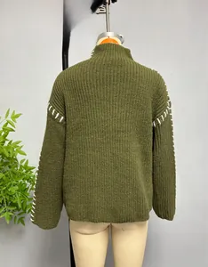 Close-up of olive green knit sweater featuring white contrast stitching on the shoulder
