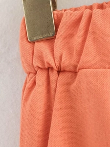 Detail of elastic waistband on coral cotton linen trousers with visible fabric texture