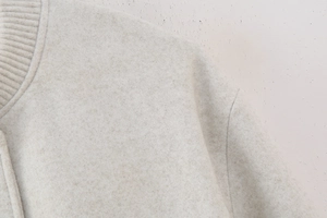 Detail of oatmeal wool bomber jacket featuring textured knit collar and premium stitching