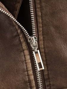 Detailed close-up of a silver metal zipper and stitching on a dark brown leather jacket