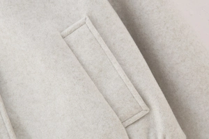 Close-up of side pocket stitching on high-quality oatmeal wool bomber jacket