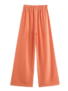 Detail of coral orange wide-leg trousers with elastic pleated waistband and smooth texture