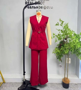 Detail of red sleeveless blazer suit with slim belt and golden triangle buckle