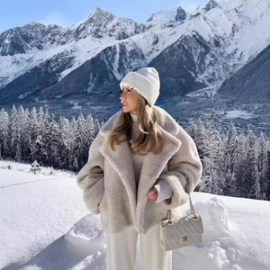 Giacca teddy da donna beige con ampi revers in un panorama montano innevato di lusso