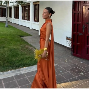 Detail of elegant halter neck maxi dress in rust orange satin with long flowing ribbon
