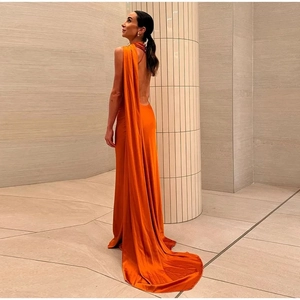 Detail of elegant orange backless satin gown featuring a long shoulder sash drape