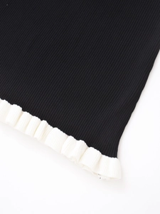 Détail du tricot côtelé présentant une base noire et un bord à volants blancs plissés