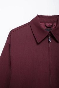 Detail of burgundy zipper jacket with metal hardware and woven fabric texture