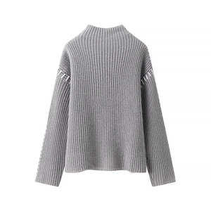 Detail of grey ribbed knit sweater featuring high neck and contrast white stitching accents