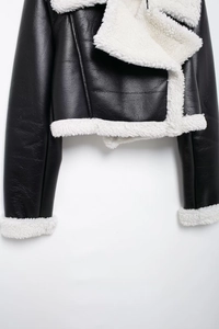 Detail of black faux leather jacket with plush white faux shearling lining and collar
